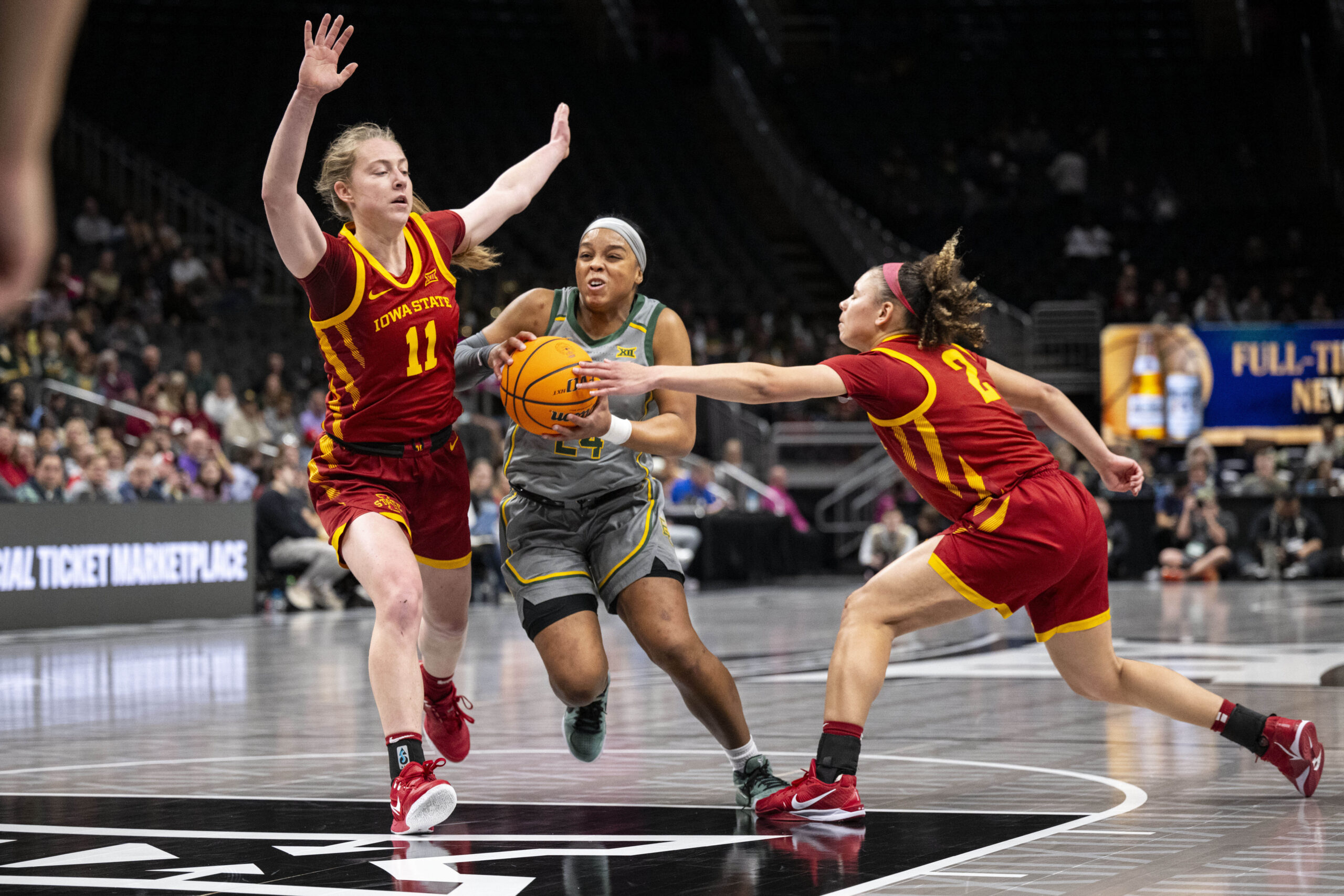 Baylor guard Sarah Andrews dribbles the ball while one Iowa State player reaches to steal it away and another one defends with her arms up in the air.