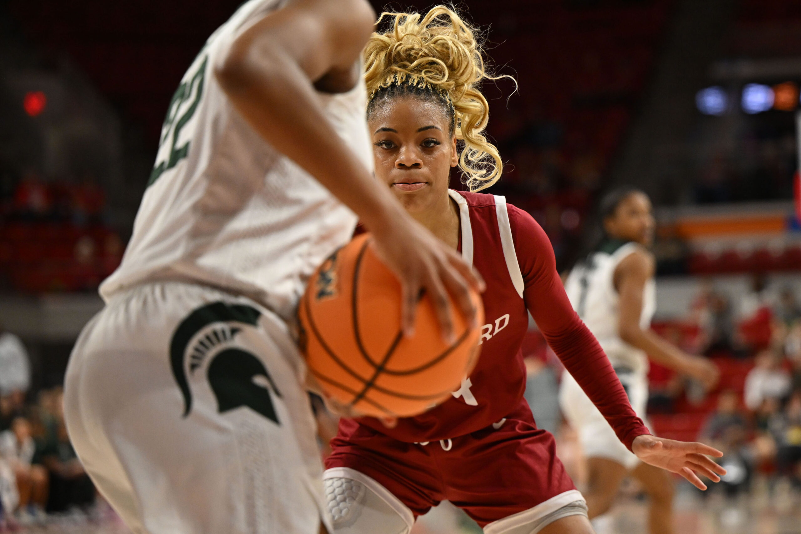 Harvard guard Harmoni Turner crouches in a defensive stance and stares at the ball Michigan State guard.