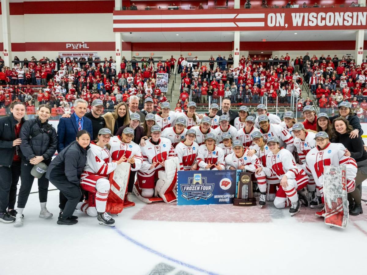 The Wisconsin Badgers gather on the ice for a photo in front of the crowd.