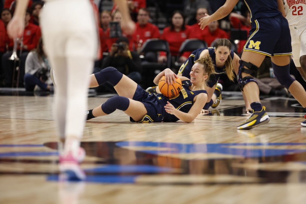 Jordan Hobbs holds onto the ball on the floor for Michigan in a Big Ten Tournament game against Ohio State on March 3, 2023 at Target Center in Minneapolis, Minn.