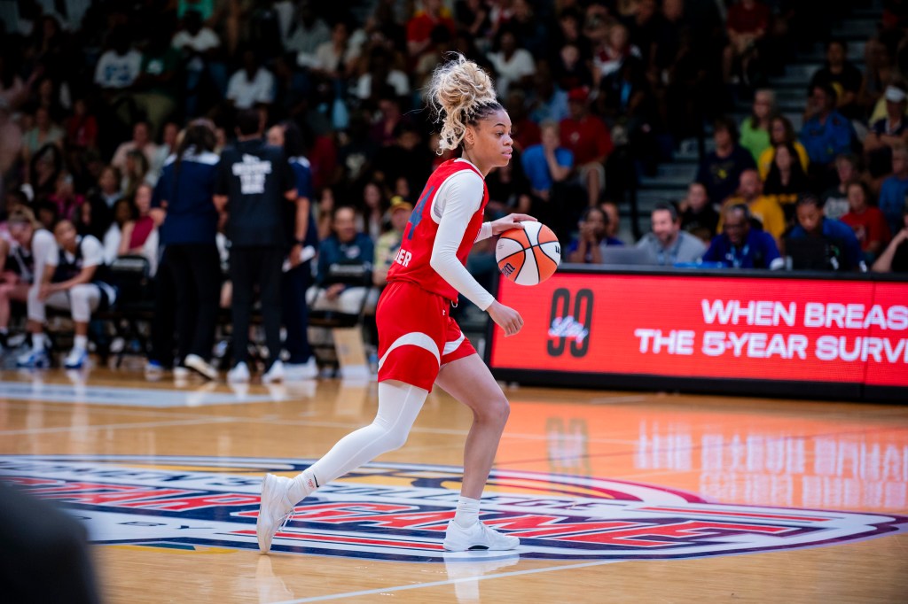 Team Lieberman guard Harmoni Turner dribbles the ball with her left hand across the half-court logo.