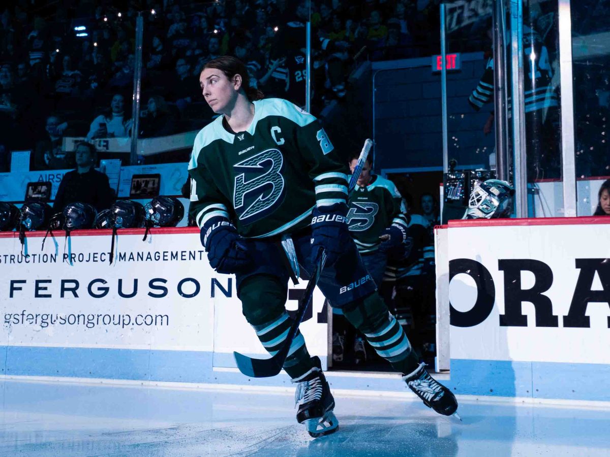 Knight skates out of the open bench door, looking to her right as she heads that way. She is wearing a green home uniform.