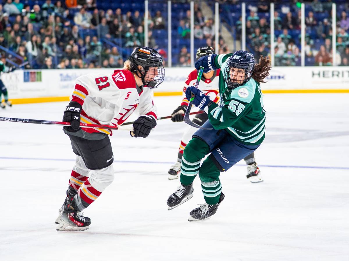 Pejšová (right in green) hunts the puck as Bell (left in white) tries to defend her.