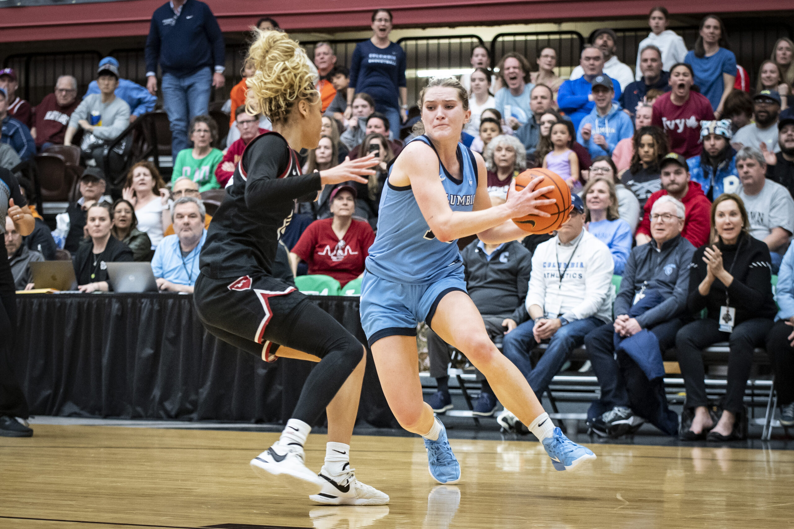 Columbia guard Kitty Henderson holds the ball with two hands on the left side of her body as she tries to step past Harvard guard Harmoni Turner.