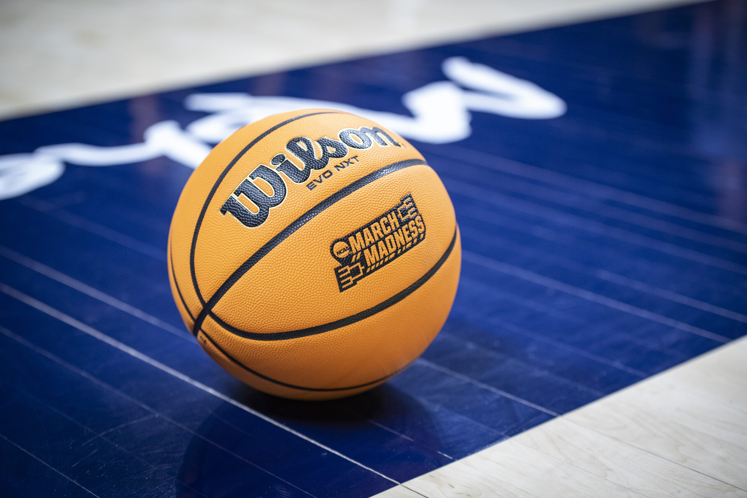 Photo of a March Madness-branded basketball on a basketball court.