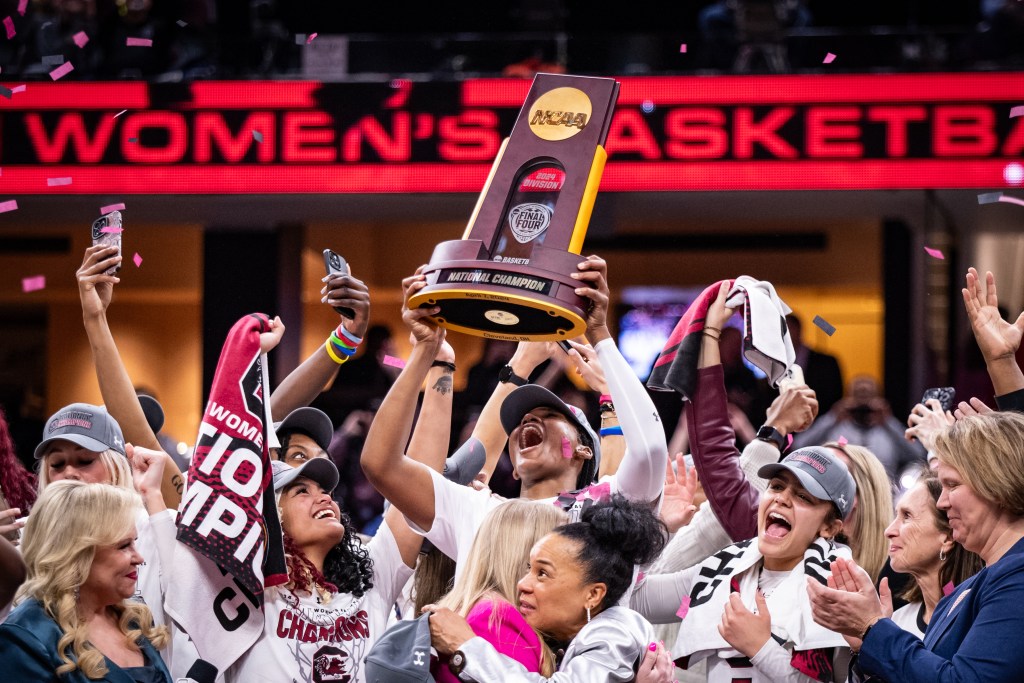 South Carolina forward Sania Feagin lifts the 2024 NCAA Tournament National Champions trophy, guard Te-Hina PaoPao on the left, after defeating Iowa on April 7, 2024 at Rocket Mortgage FieldHouse in Cleveland, Ohio.