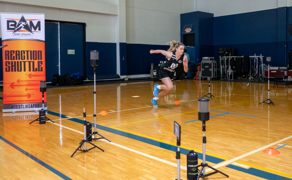 Columbia guard Kitty Henderson sprints between cones during a combine event. Sensors and cameras are set up to record her performance.