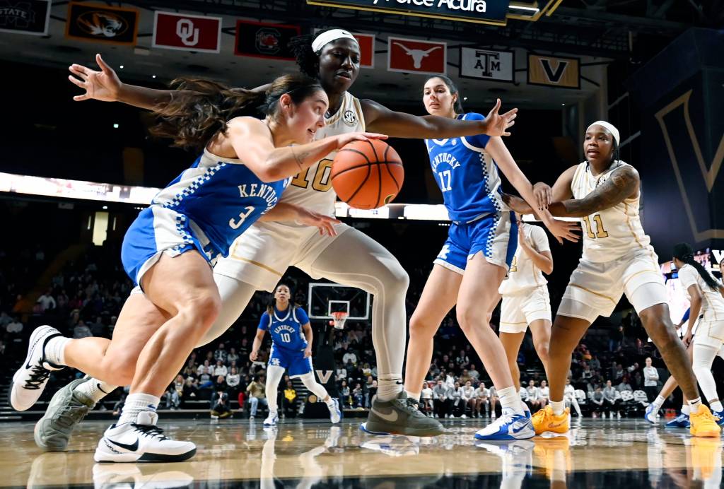 Kentucky guard Georgia Amoore dribbles the ball with her right hand along the baseline. Vanderbilt forward Jane Nwaba slides her feet and stretches her arms out to defend her.