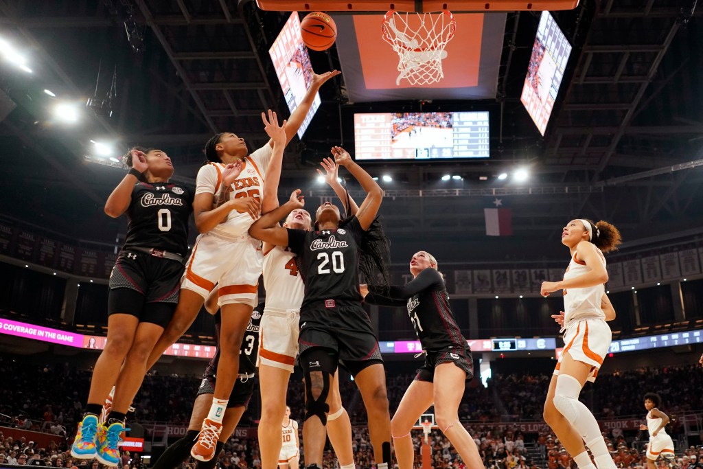 Texas forward Madison Booker attempts a left-handed layup on the right side of the basket in a crowd of both South Carolina and Texas players.