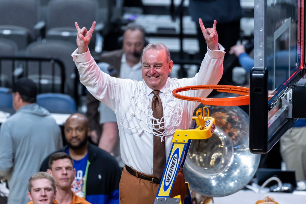 Vic Schaefer stands on top of the ladder with the net draped over him to celebrate Texas heading to the Final Four.