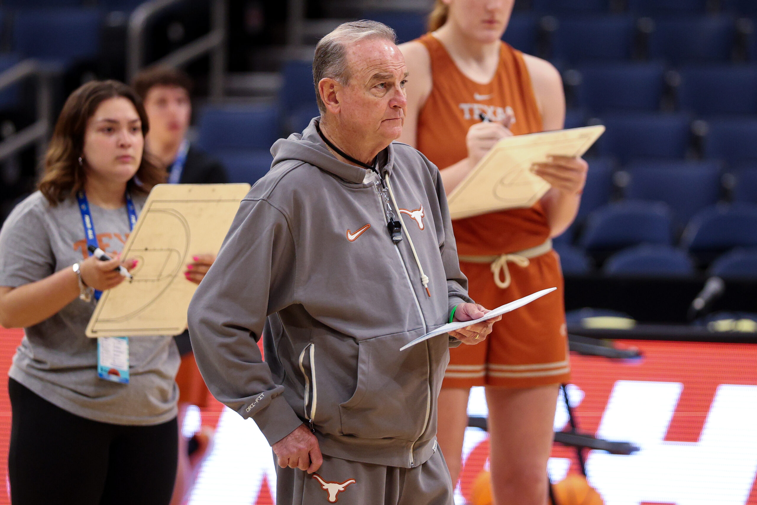 Texas head coach Vic Schaefer wears a gray Longhorns sweatsuit and holds a piece of paper in his left hand during practice.