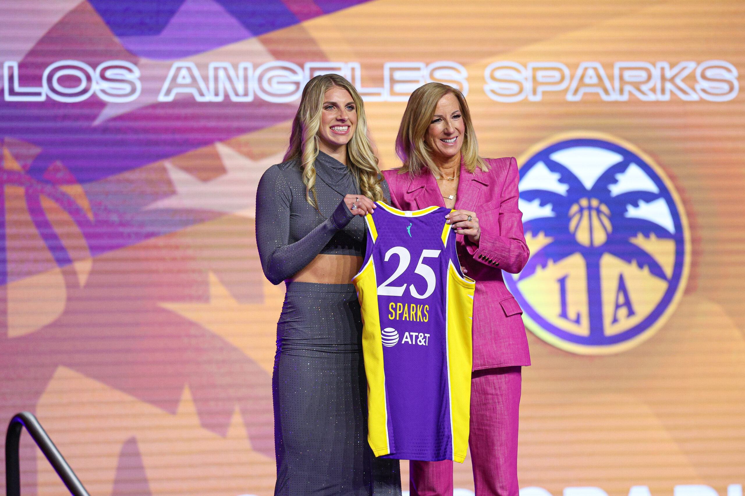 Sarah Ashlee Barker smiles with WNBA Commissioner Cathy Engelbert and holds up a Los Angeles Sparks jersey.