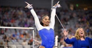 A gymnast and her coach celebrate after an uneven bars routine.