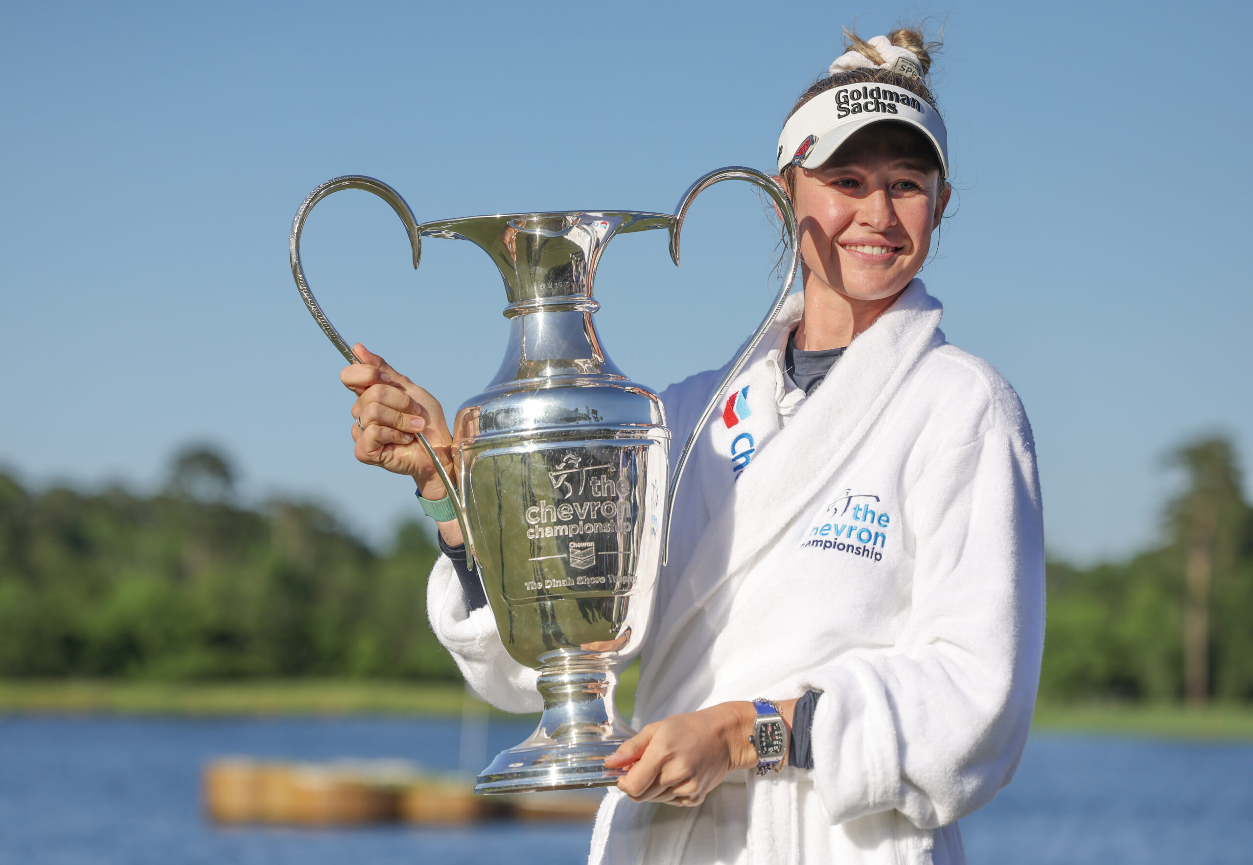 Nelly Korda, 2024 Chevron Championship winner, holds up the tournament trophy to her right and smiles.