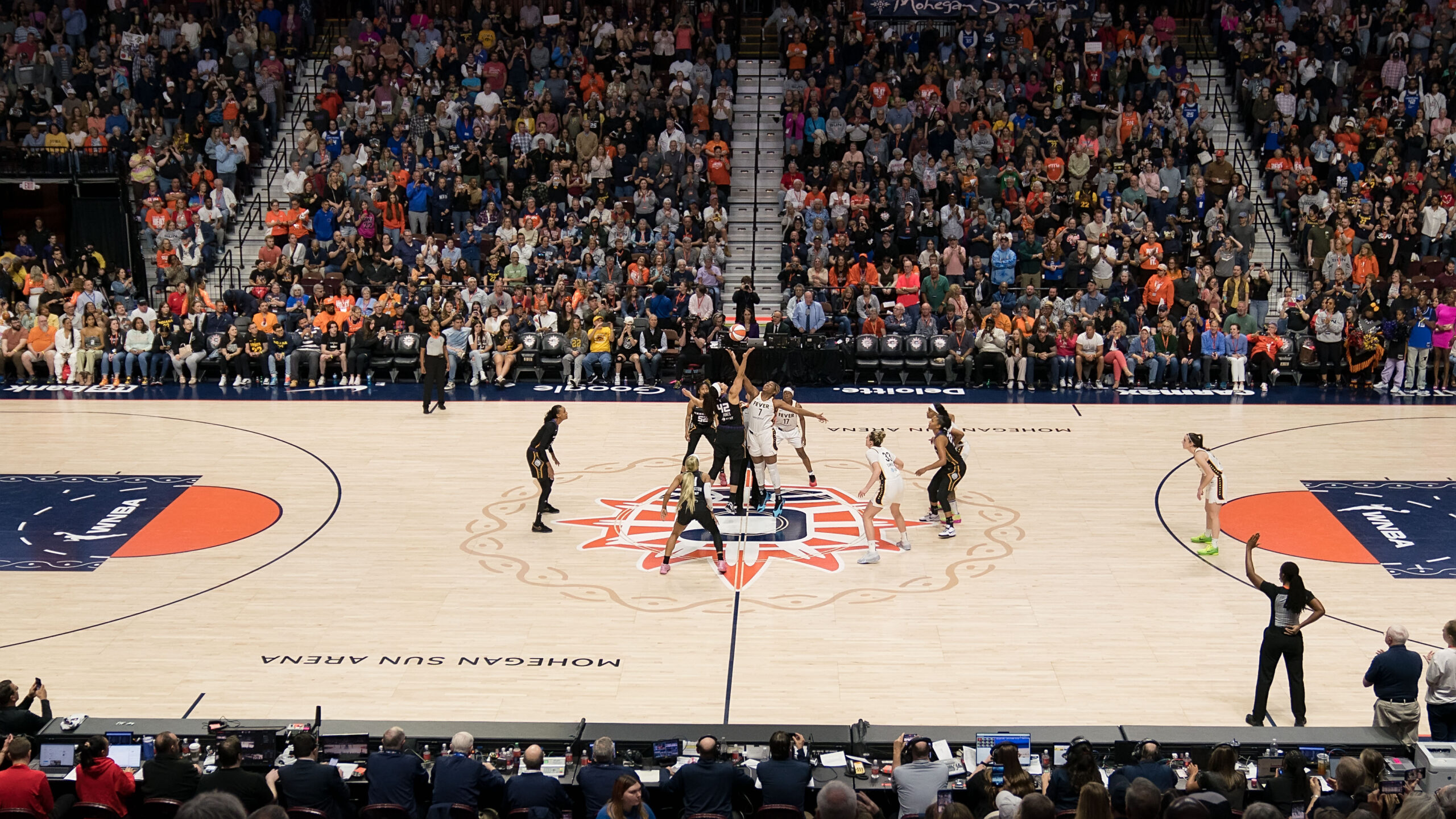 Players jump for the ball at center court of a packed Mohegan Sun Arena.