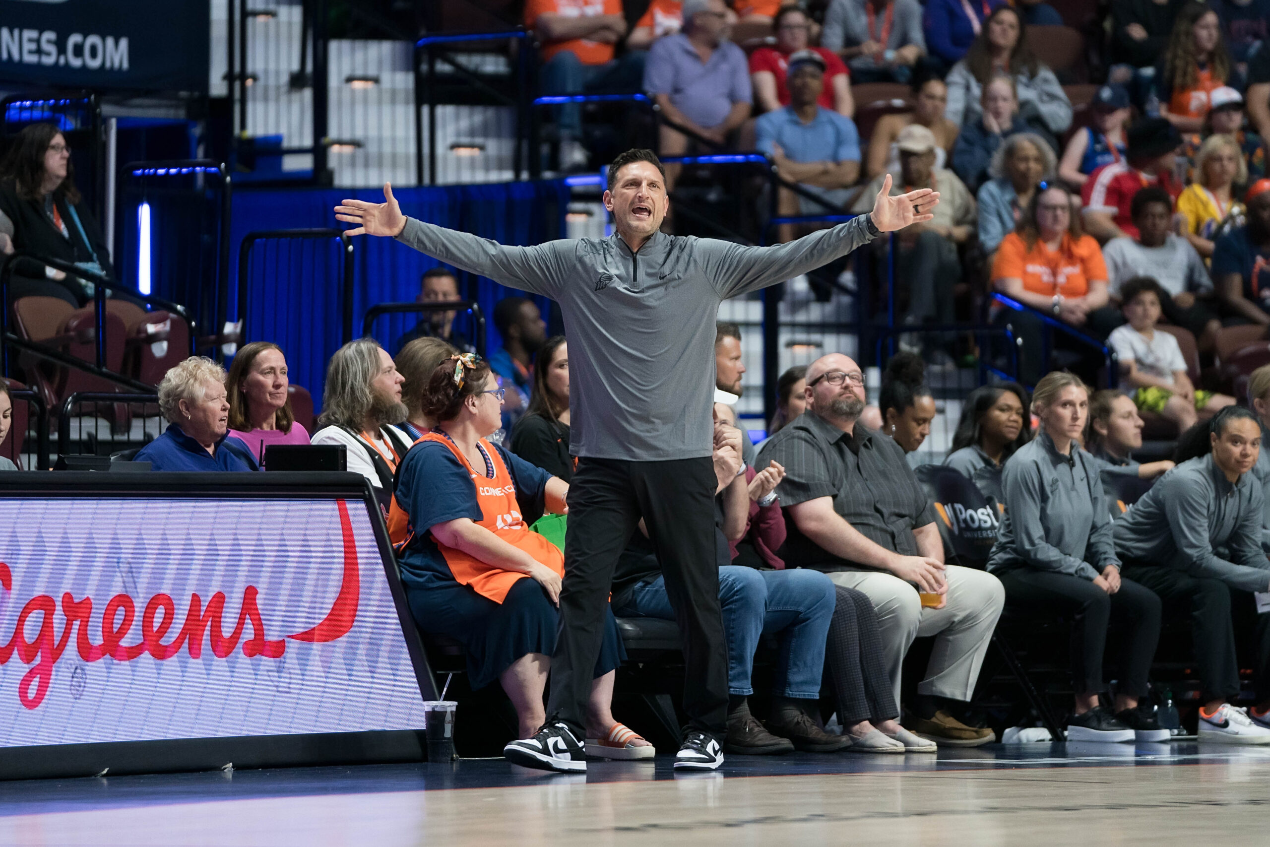 Nate Tibbetts stands with his arms outstretched to the sides yelling as he coaches for the Phoenix Mercury.