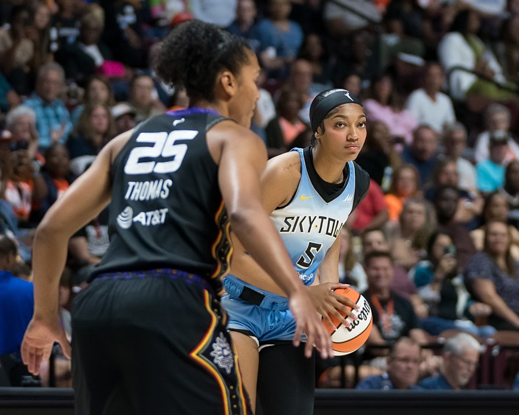 Chicago Sky forward Angel Reese holds the ball at her waist while looking to pass while Connecticut Sun forward Alyssa Thomas stands with arms slightly extended