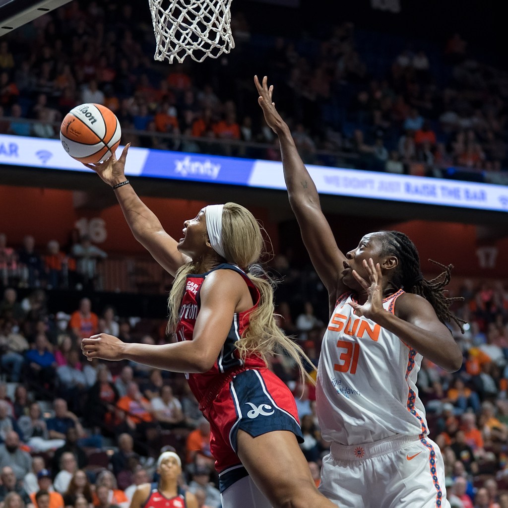 Washington Mystics forward Kiki Iriafen extends for a right-handed layup on the far side of the basket to avoid being blocked from behind by Connecticut Sun center Tina Charles.