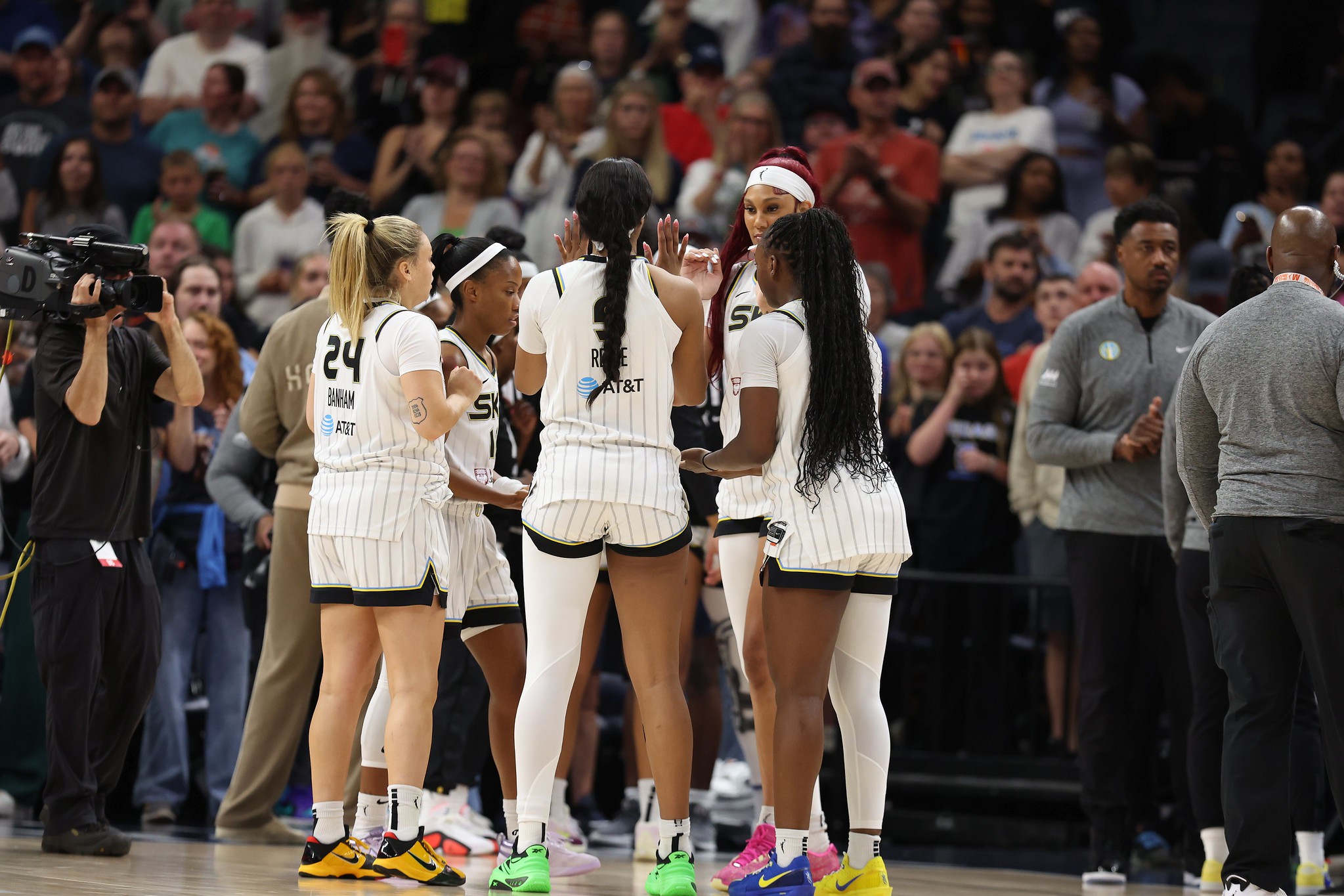 Chicago Sky players stand in a circle while Angel Reese holds hands up for a hi-five
