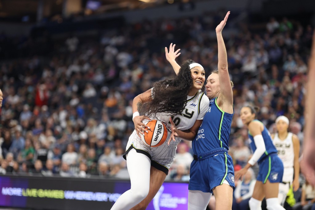 Chicago Sky center Kamilla Cardoso leans forward with the ball in her hands looking at the basket while Alanna Smith raises her arms in front of her