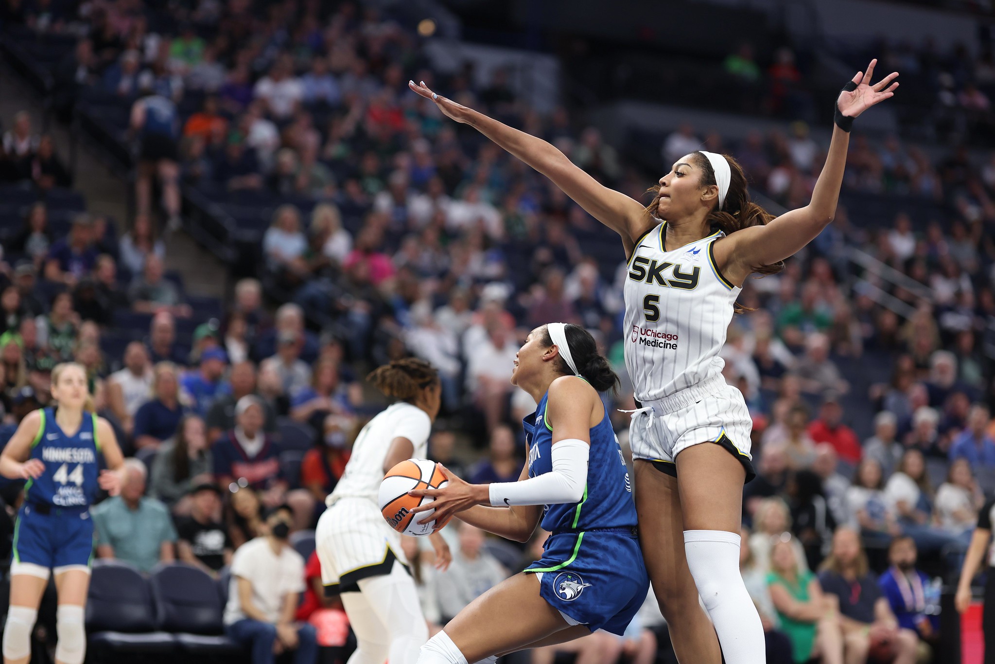 Chicago Sky forward Angel Reese extends right hand over Napheesa Collier who holds ball with both hands while back is to Angel Reese