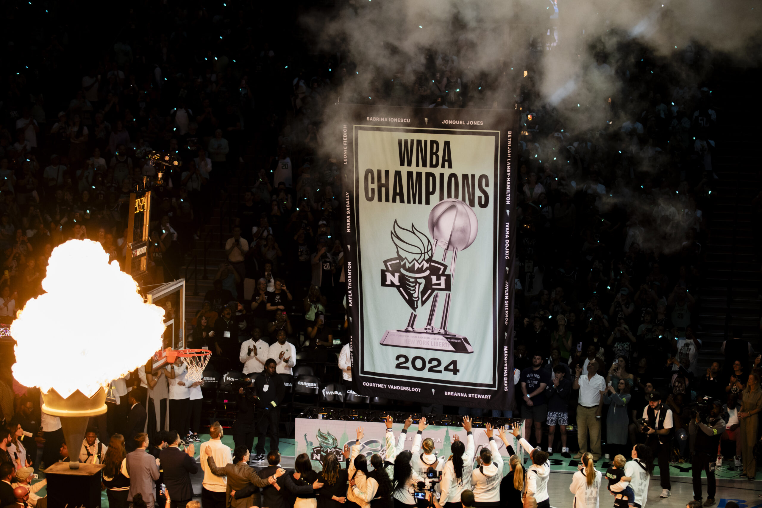 The New York Liberty's championship banner rises while the torch flames up.