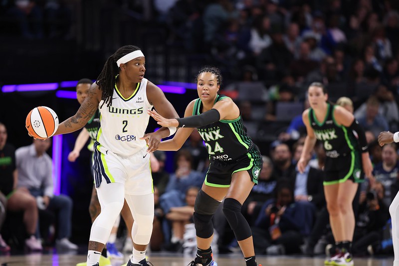 Dallas Wings forward Myisha Hines-Allen turns to her right and holds the ball with her right hand, away from Minnesota Lynx forward Napheesa Collier.