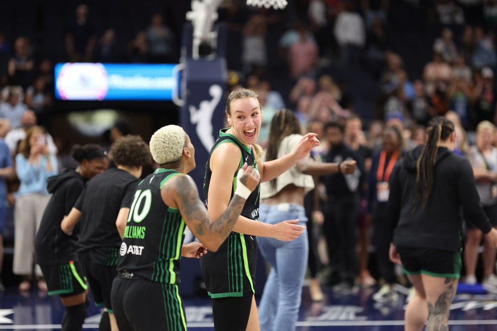 Alanna Smith (center) smiles at Courtney Williams (left) in front of a basketball hoop