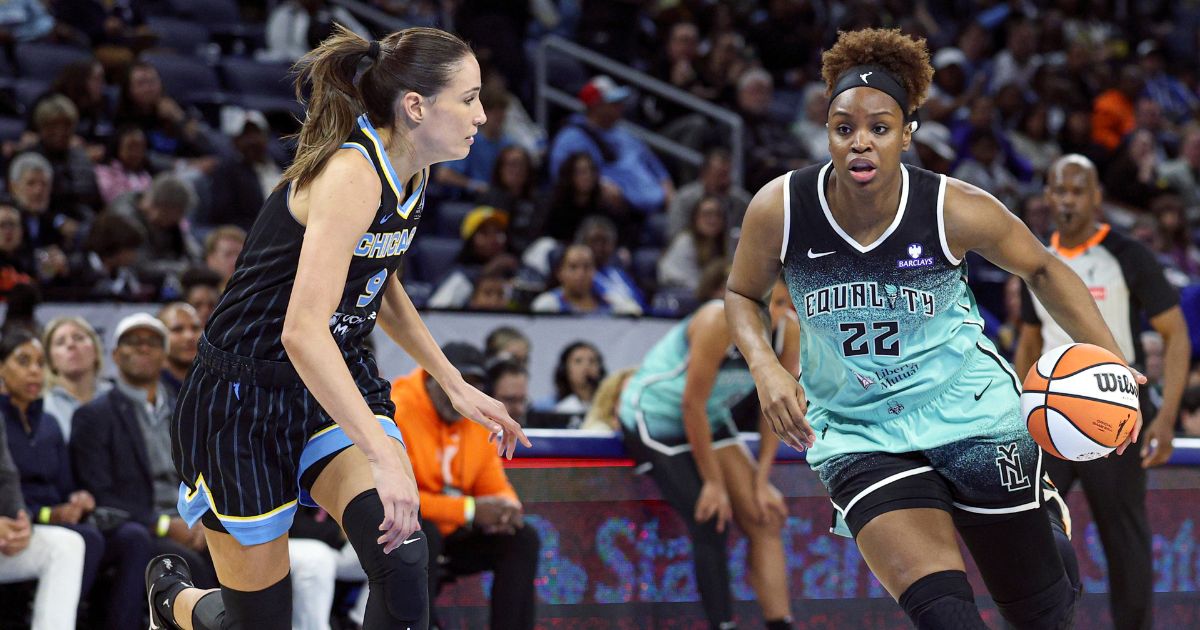 Kennedy Burke drives with the basketball wit her head up while Rebecca Allen guards her.