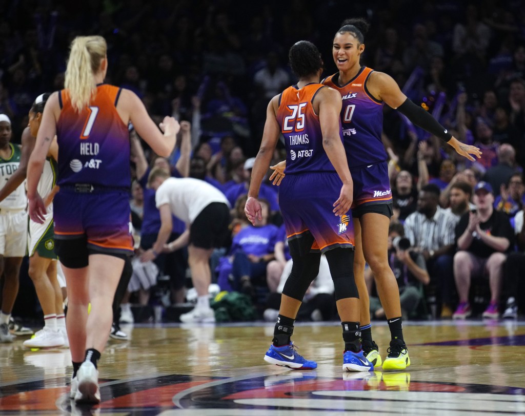 Alyssa Thomas (25) chest bumps Satou Sabally (0) while Lexi Held (1) walks over to join the celebration