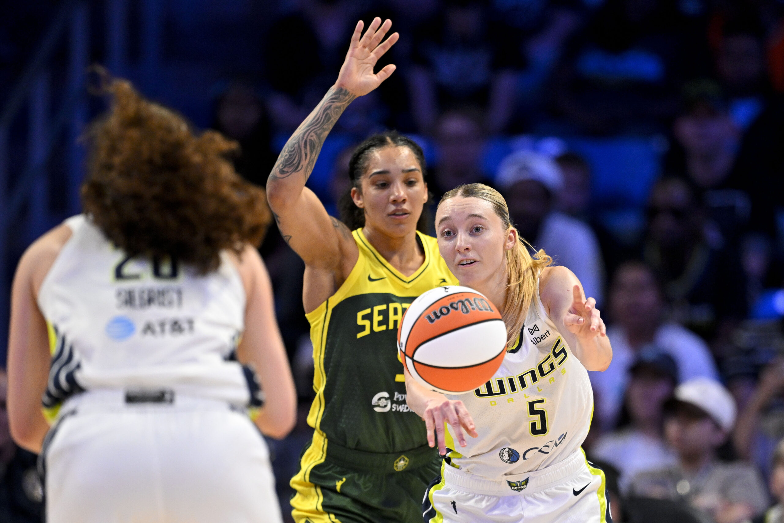 Paige Bueckers passes the ball away from a defender to teammate Maddy Siegrist for the Dallas Wings.