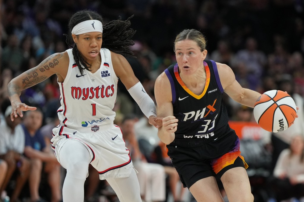 Phoenix Mercury guard Sami Whitcomb dribbles the ball with her left hand. Washington Mystics guard Sug Sutton moves her feet to try to stay with Whitcomb.