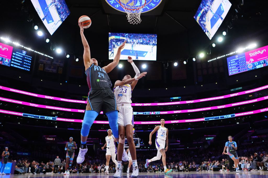 Brionna Jones, in a black and blue Atlanta uniform, drives to the basket for a layup over a defender in a white uniform 