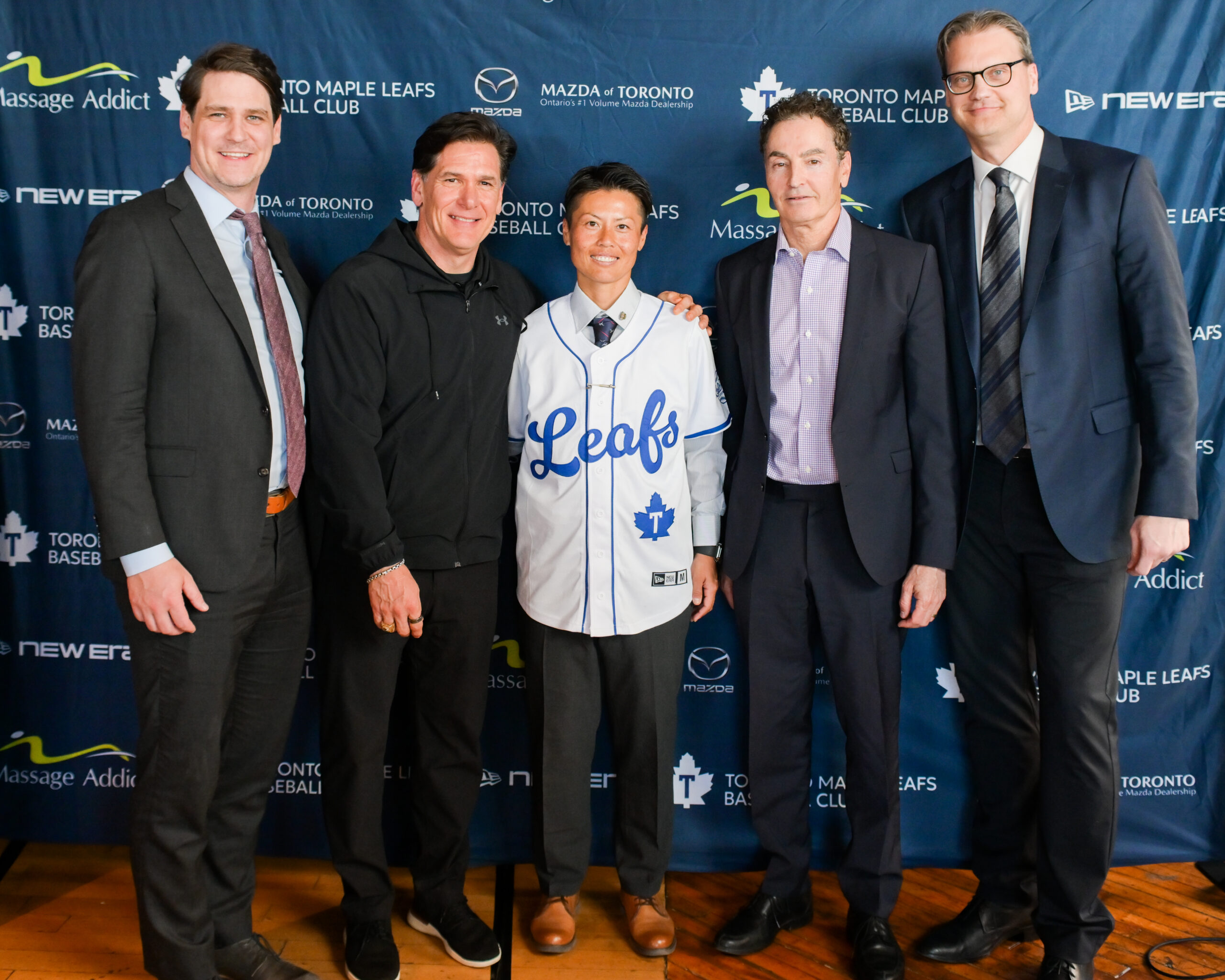 Ayami Sato smiles for a photo with Toronto Maple Leafs executives at a press conference.