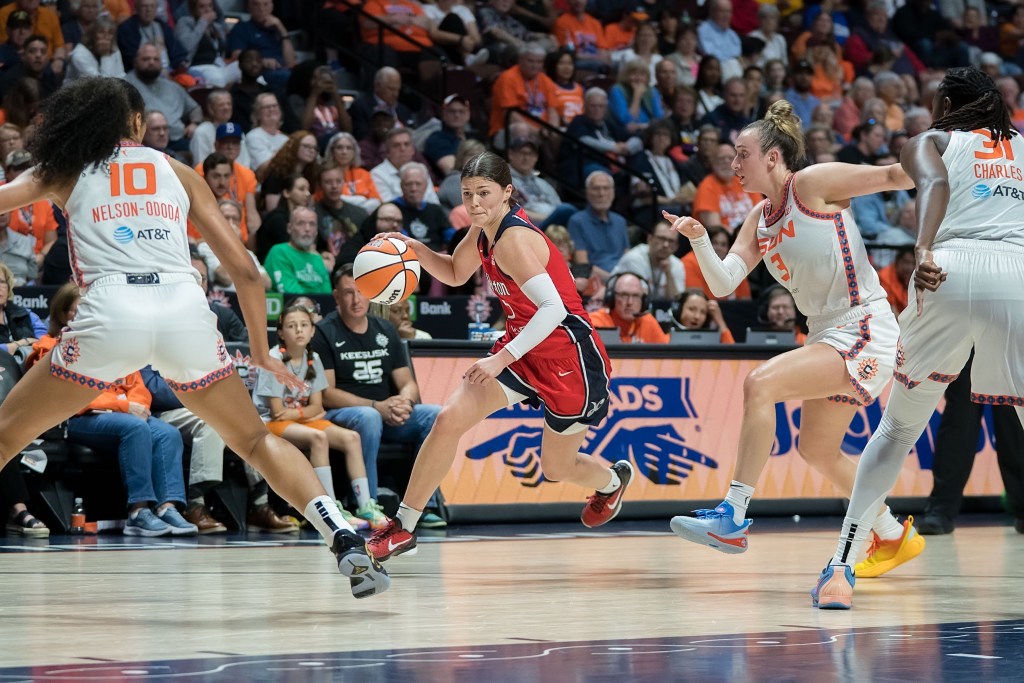 Washington Mystics guard Jade Melbourne dribbles the ball with her right hand. At least three Connecticut Sun defenders are looking at her, and one is sliding over to help because Melbourne has a step on her primary defender.