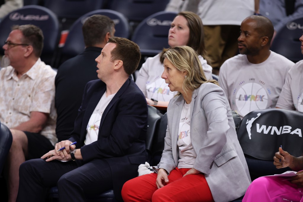 Minnesota Lynx associate head coach Eric Thibault and head coach Cheryl Reeve sit on the bench next to one another. They are both looking to their right, at the action on the court.