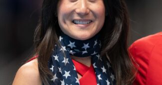 A woman draped in an American flag scarf smiles for the camera.