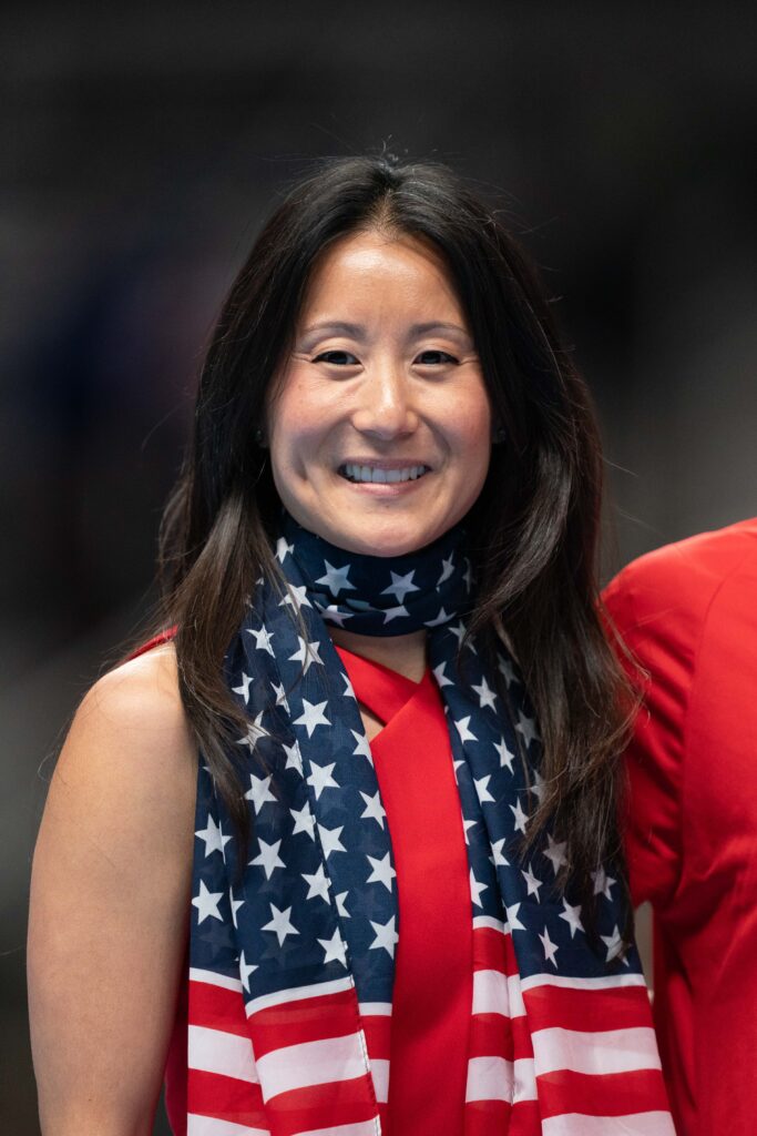 A woman draped in an American flag scarf smiles for the camera.