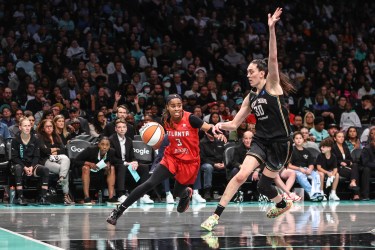 Jordin Canada, wearing a red Atlanta Dream jersey, drives past Breanna Stewart, wearing a black New York Liberty jersey