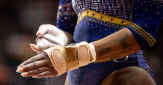 A Black gymnast's hands, wearing bar grips for Fisk University.