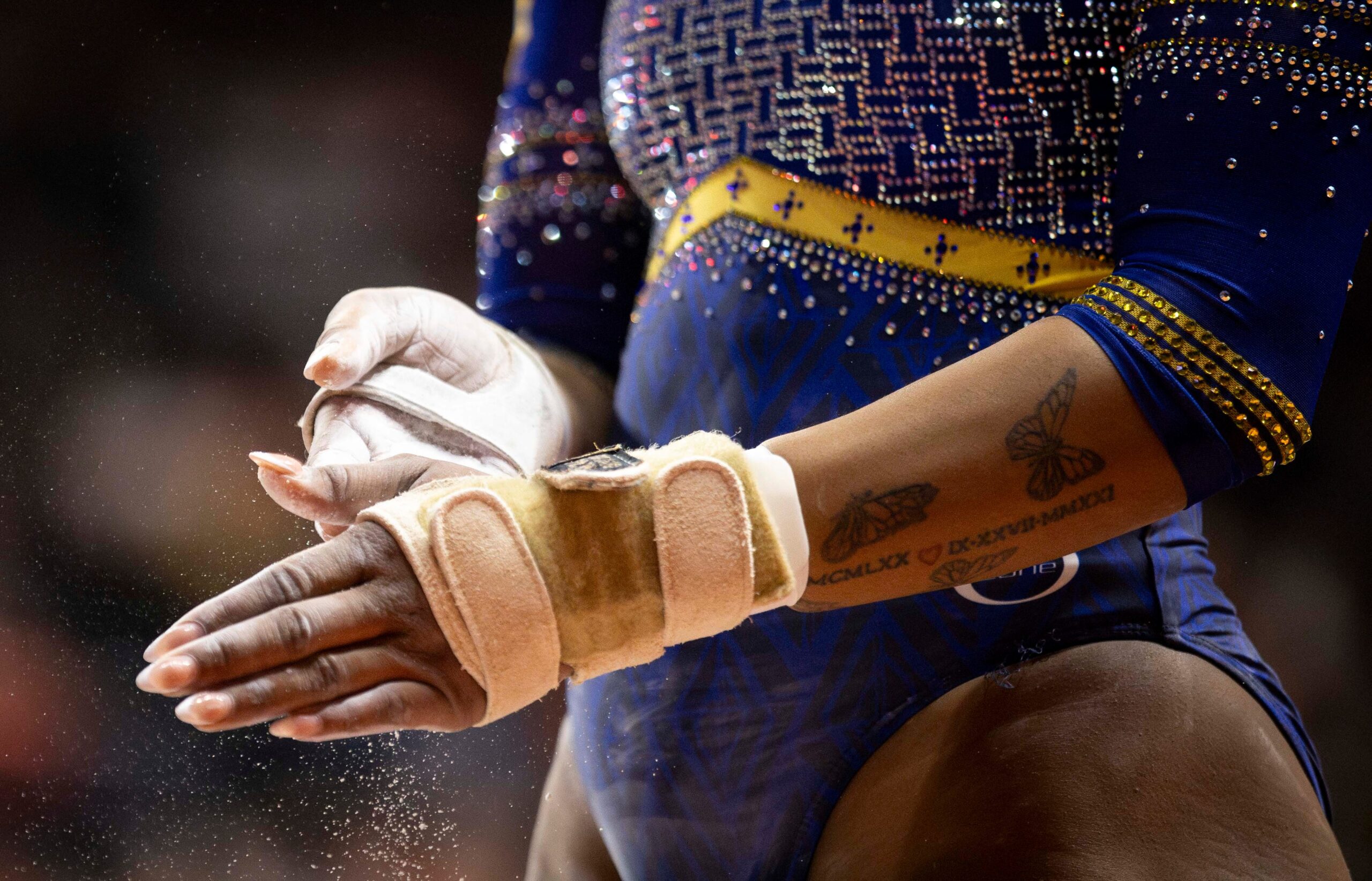 A Black gymnast's hands, wearing bar grips for Fisk University.