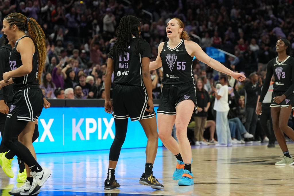 Golden State Valkyries forward Chloe Bibby and guard Tiffany Hayes celebrate together. Bibby is show from the front while Hayes is shown from the back. A packed but out-of-focus crowd is in the background behind them.