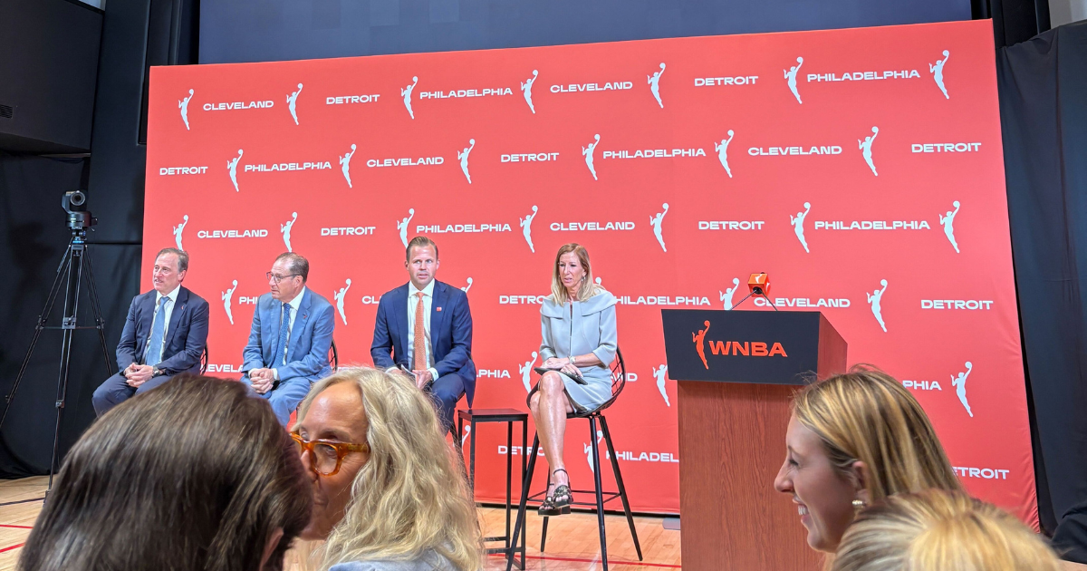 WNBA executives sit in front of a branded backdrop with the cities Cleveland, Detroit and Philadelphia listed between logos.