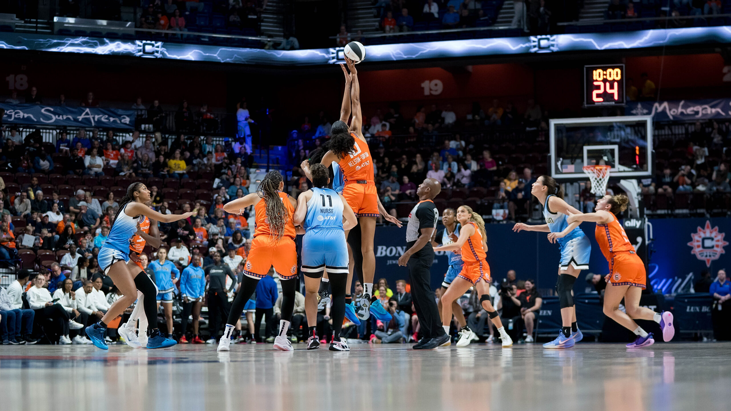 Players jump in the air for the ball during tip-off.