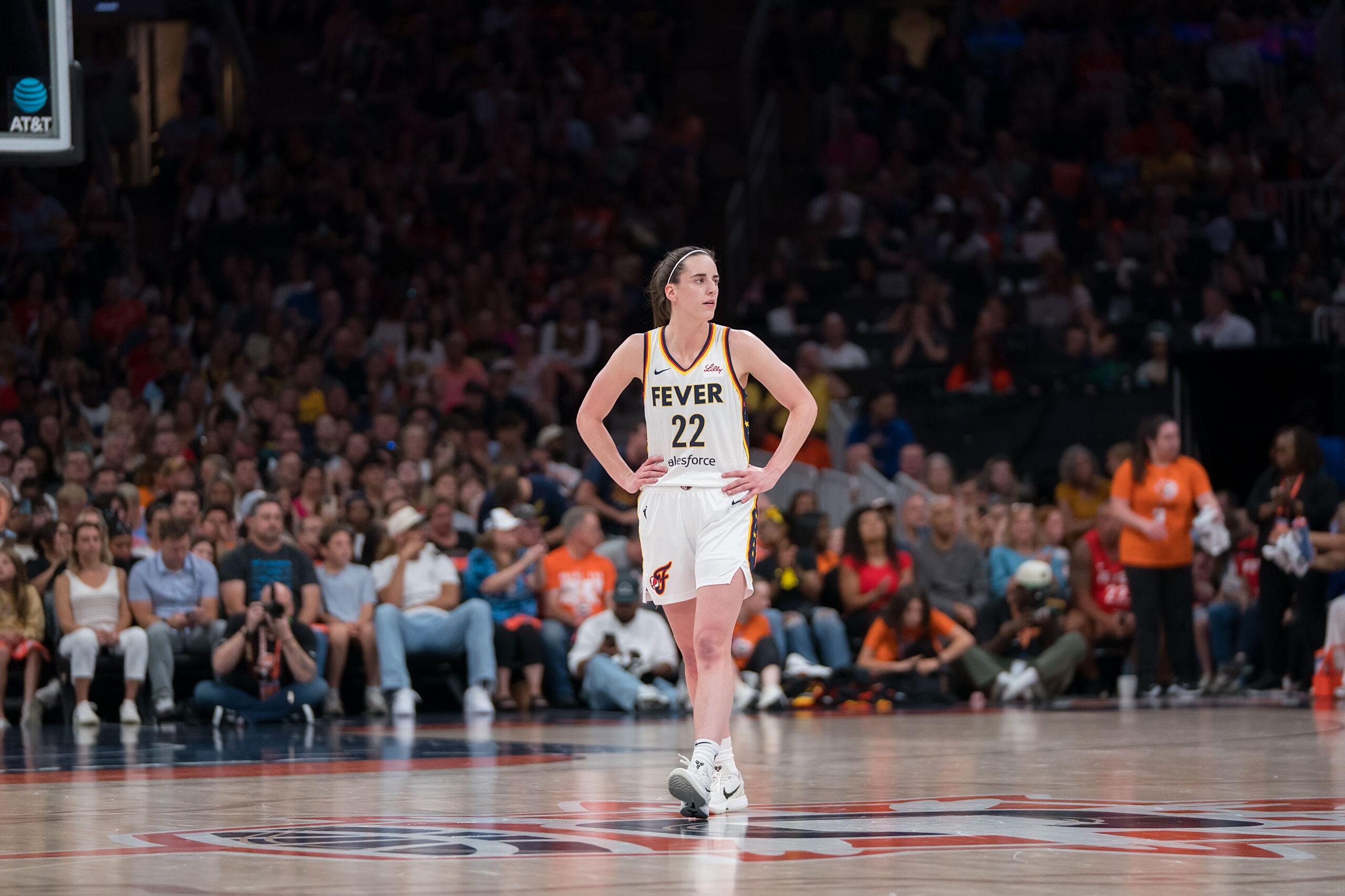 Indiana Fever guard Caitlin Clark stands in the middle of the court in a white uniform