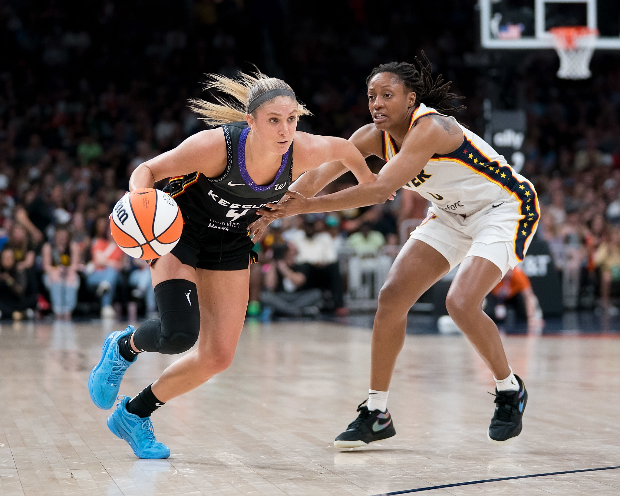 Connecticut Sun guard Jacy Sheldon dribbles while defended by Indiana Fever guard Kelsey Mitchell