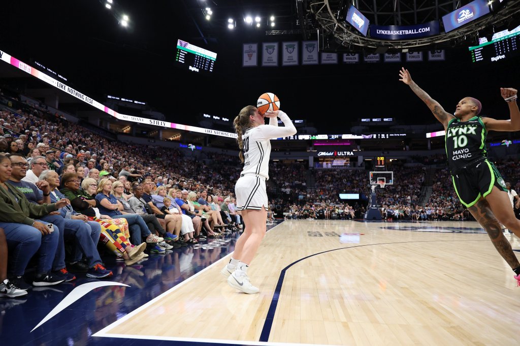 Golden State Valkyries guard Kate Martin prepares to shoot over Minnesota Lynx guard Courtney Williams. They are shown from the side with a large crowd to the side and behind them.