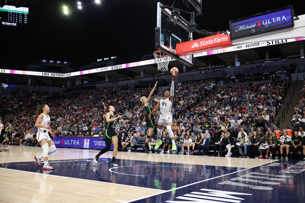 Golden State Valkyries forward Kayla Thornton shoots a layup over Minnesota Lynx guard Natisha Hiedeman. They are shown from the side with a large crowd behind them.