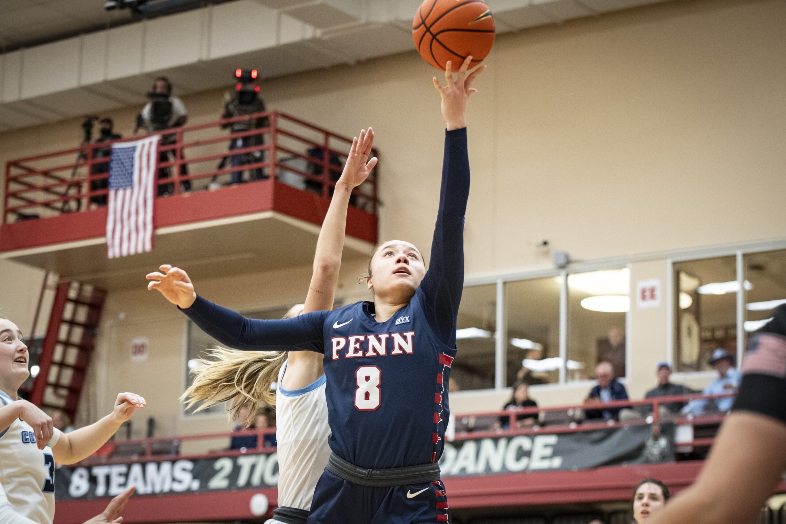 Penn guard Sarah Miller attempts an underhanded layup with her left hand. The ball is just about to leave her fingertips. A Columbia defender tries to contest it from behind but can't get her hand close enough.
