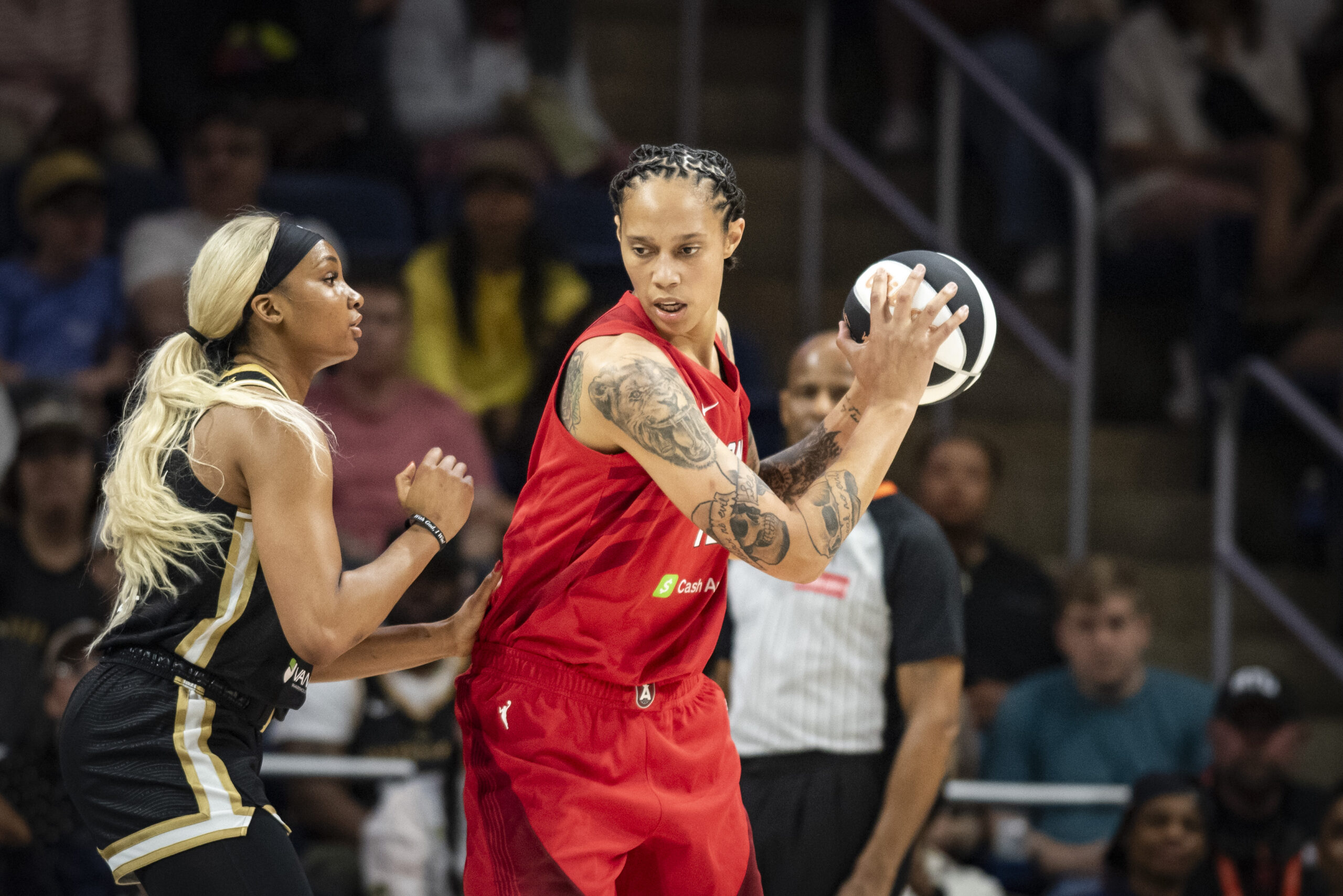 Atlanta Dream center Brittney Griner (42) holds the ball with two hands with her body turned to the side while being defended by Washington Mystics forward Kiki Iriafen (44)